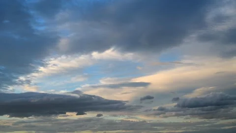 Time lapse of multicolored pastel shaded clouds move across a light blue sky.  Stock Footage 279657464