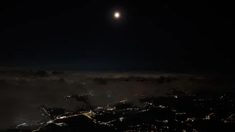 Time lapse night aerial of full moon above low clouds over distant city lights Vídeo Stock 342647315