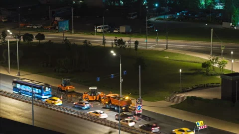 Time lapse. Night city. Several big asphalt rollers work on the busy highway Stock Footage 254228548