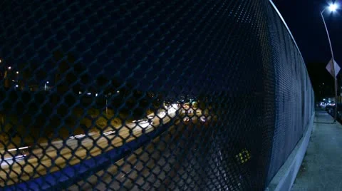 Time Lapse of Night Traffic behind Wire Fence Stock Footage