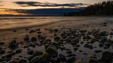 Time lapse of ocean tide going out with a zoom in at sunrise that ends with a Stock Footage 129534619