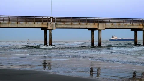 Time lapse of ocean waves under a pier at dusk as a ship goes out to sea. Stock Footage 236965417