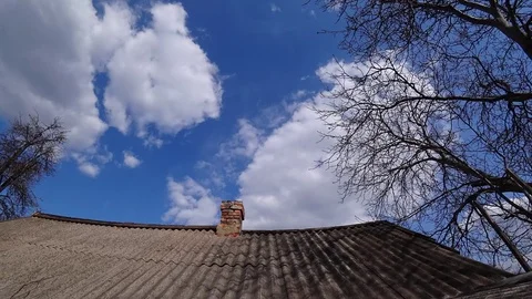 Time lapse of old brick chimney on a tiled roof against a cloudy sky on a sunny Stock-Footage 105804611