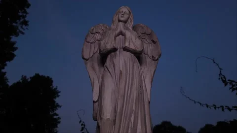 Time lapse pan up over angel statue with evening sky turning into night Stock Footage 138127550