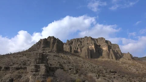 Time lapse partly cloudy sky drifting over a rugged rocky steppe hill - Climate Stock Footage 339557937