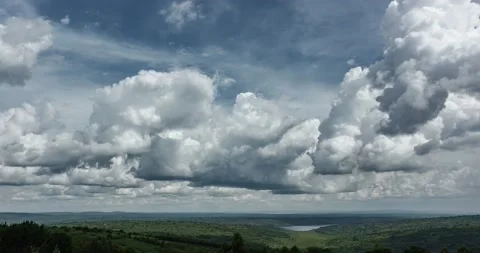 Time lapse of passing clouds (cumulus) from a hill top overlooking green fields. Stock Footage