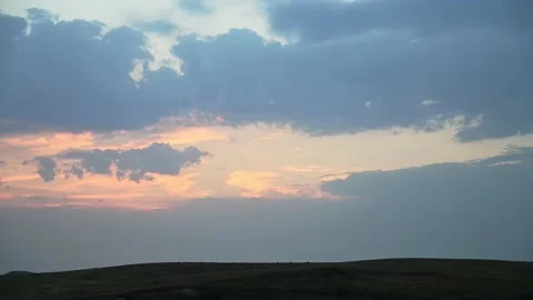 Time lapse of pastel colored evening sky and clouds over a dark grassy landscape Stock Footage 220684200