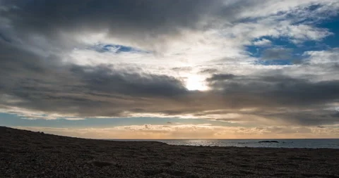 Time lapse on pebble beach at dusk with sun obscured behind flat clouds Stock Footage 146072917