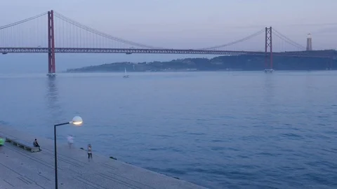 Time lapse of pedestrians across from the iconic '25 of April' Bridge in Lisbon Stock Footage 103822734