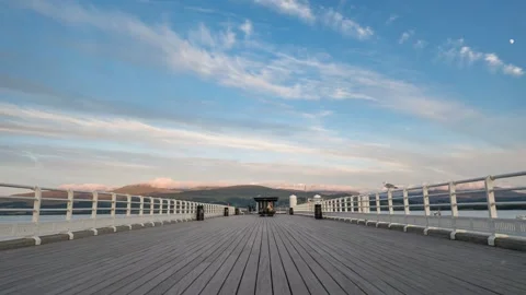 Time lapse of people walking down Beaumaris Pier in North Wales as the sun sets Stock Footage 255230265