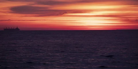 Time-lapse of perfect orange-red sunset beyond the clouds near dark sea waves. Stock Footage 151602449