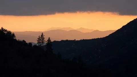 Time lapse of pine trees on a mountain ridge silhouetted by sunset light Stock Footage 98907574