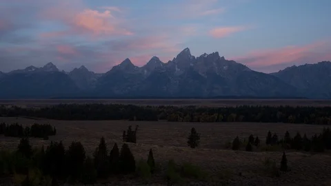 Time lapse of pink sunrise clouds behind snowy Grand Teton mountains Stock Footage 95247169