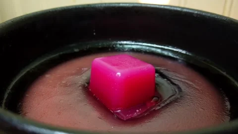 Time lapse of pink wax cube melting inside black metal pan. Stockbeeldmateriaal 337155159