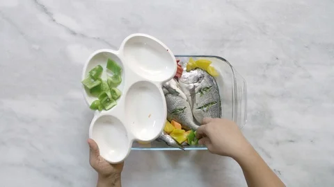 Time lapse of preparing sea bream: adding vegetable, oil, and spices Stock Footage 122235567