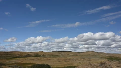 Time lapse of puffy white clouds in a blue sky above a dry landscape  Stock Footage 233116077