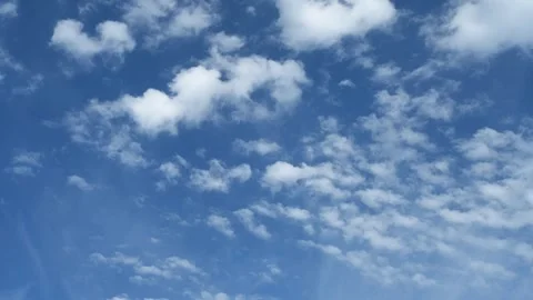 Time lapse of puffy white summer clouds moving across a pale blue sky Stock Footage 319155622