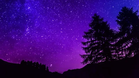 Time lapse purple night sky stars over mountain and tree silhouette Stock Footage 77979254