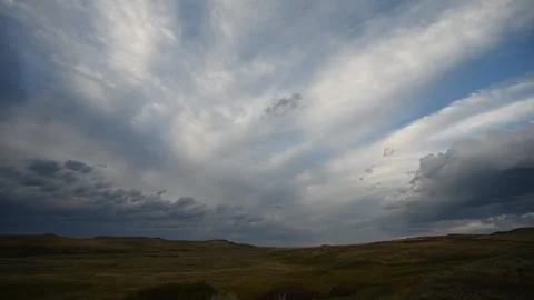 Time lapse of radiating summer clouds moving above rolling dry prairie grass and Stock Footage 306541794