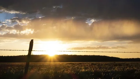 Time lapse of rain and clouds in front of a golden sunset Video stock 135807876