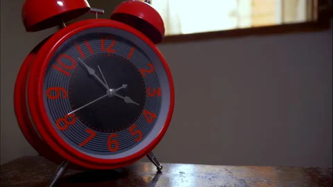 Time-Lapse of a Red Retro Alarm Clock on a Wooden Table by an Open Window Stock Footage 337888650