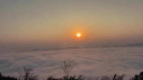 Time-lapse of red sun rising over a flowing sea of clouds. Video stock 328689699