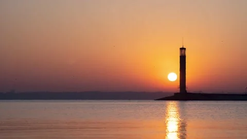 Time lapse of a red sunrise over a vast lake or sea with a lighthouse. Video stock 199310941
