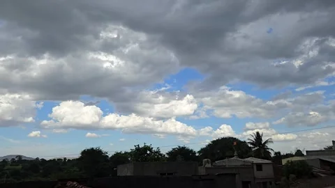 A time-lapse reveals dark monsoon clouds racing across a blue sky, flickering wi Stock Footage 337350346