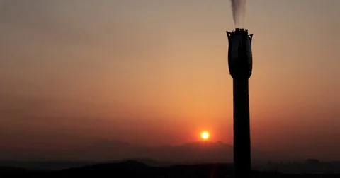Time lapse of rising sun through gray clouds behind chimney of factory :4K Stock Footage 73498736