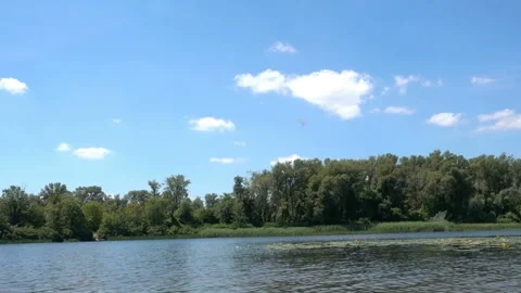 Time lapse of a river and white clouds in a blue sky. Video stock 134833774