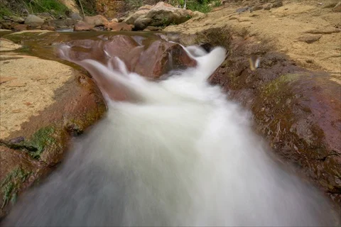 Time lapse of river rushing between volcanic rocks Stockbeeldmateriaal 91122533