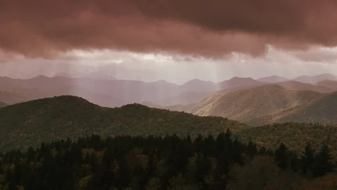 Time-lapse of rolling clouds over the forest covered mountain ranges at dusk Stock Footage 103395283