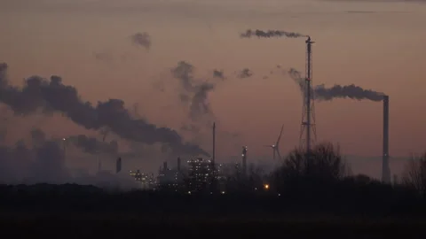 Time lapse with rotating windmill blades and smoke from oil and gas refinery. Video stock 257491538