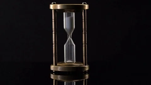 Time Lapse of Sand Flowing Through vintage metal hourglass on black background Video stock 75964455