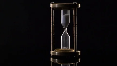 Time Lapse of Sand Flowing Through vintage metal hourglass on black background Video stock 75964968