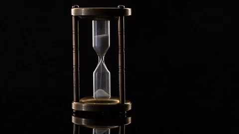 Time Lapse of Sand Flowing Through vintage metal hourglass on black background Video stock 75965128