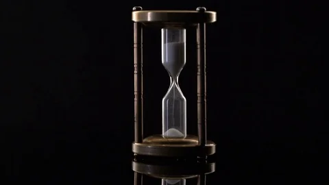 Time Lapse of Sand Flowing Through vintage metal hourglass on black background Video stock 75967451