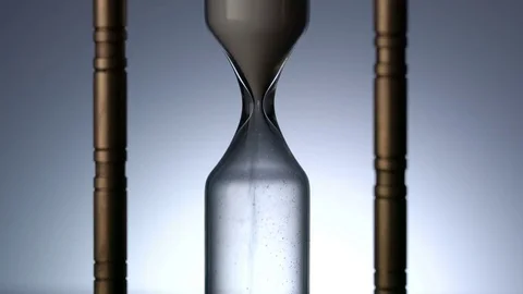 Time Lapse of Sand Flowing Through vintage metal hourglass on grey background Video stock 75967895