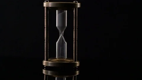 Time Lapse of Sand Flowing Through vintage metal hourglass on black background Video stock 75968724