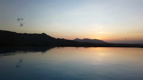 Time lapse of a scenic orange sunset reflecting in infinity pool surrounded Video stock 121209671