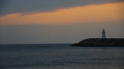 Time lapse of sea waves at colorful sunset on ocean beach with a lighthouse Stock Footage 59131708
