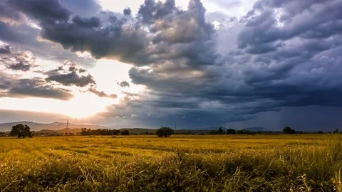 Time lapse sequence of sunset with storm clouds over golden fields Stock Footage 76329234
