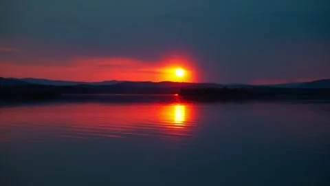 A time-lapse of the setting sun against the backdrop of a calm freshwater lake. 動画素材 334648541