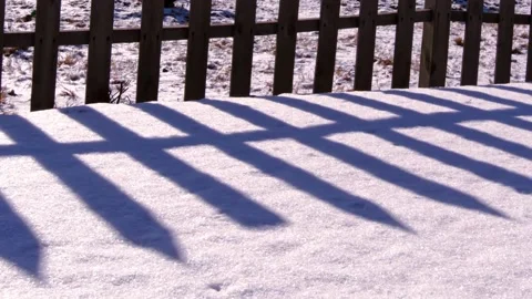 Time-lapse shot of changes of light and shadow of the wooden fence on the snow Stock Footage 152498012