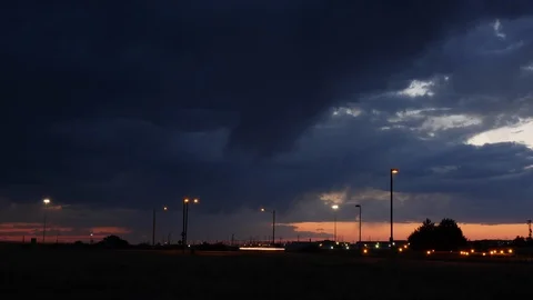 Time-lapse shot of dramatic storm clouds after sunset with traffic and Stock Footage 104442439