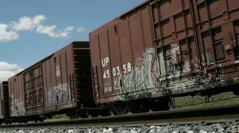 Time lapse shot of fluffy white clouds passing over old railroad boxcars. Stock Footage 11520948