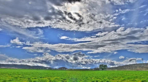 Time-lapse shot of thick cluds over green meadows in Utah with lens flare Video stock 52327769