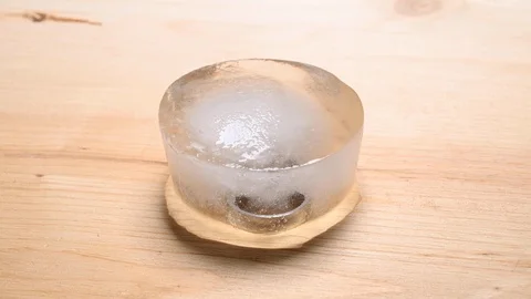 Time-lapse that shows how ice cubes melt with 2 wedding bands inside Stock Footage 115122351