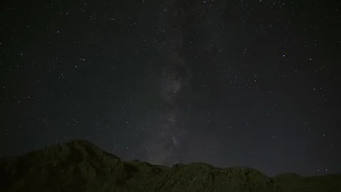 Time lapse shows Milky Way stars emerging above mountain peaks after sunset Video stock 339368634