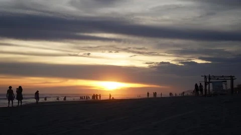 Time lapse of the silhouettes of a crowd at sunset on the beach fade away. Stock Footage 247528409